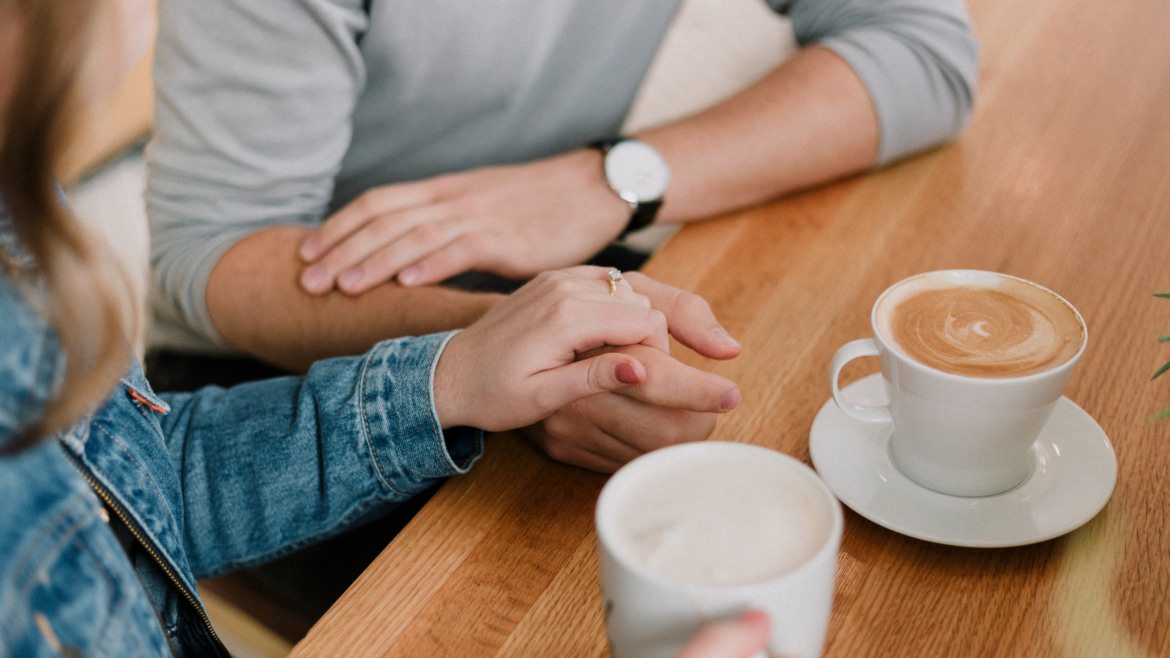 Verlobtes Paar halten Händchen und Trinken Kaffee